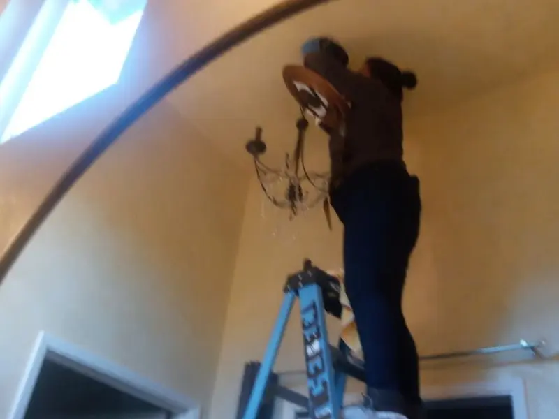 Electrician installing a chandelier in a Lealman residence